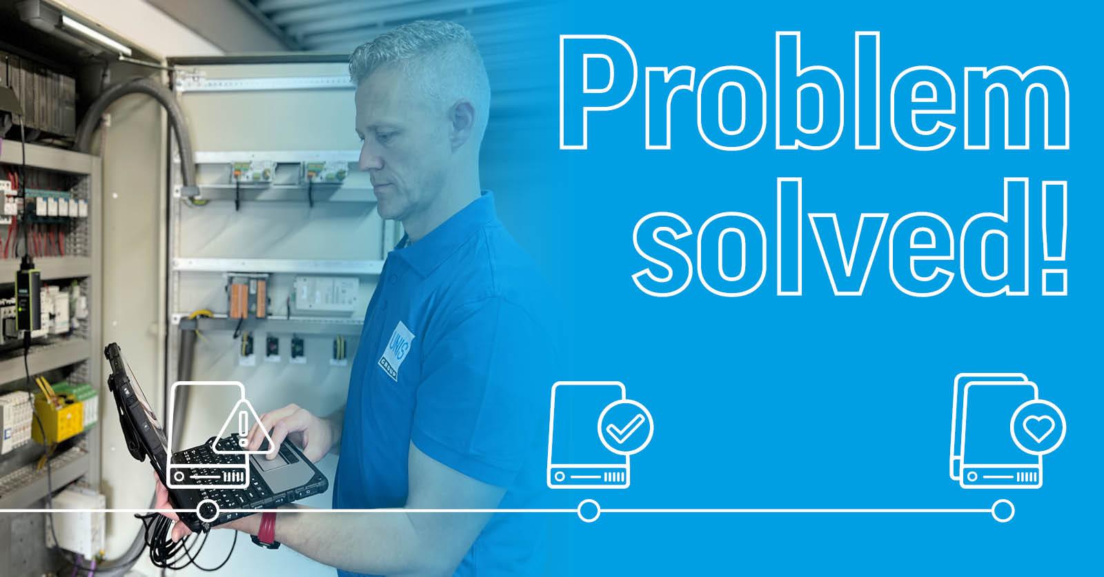 Technician using a laptop while working on industrial electrical equipment inside a control cabinet.